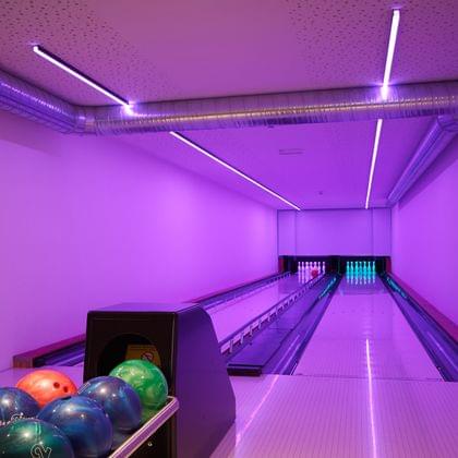 Modern bowling alley with neon purple lighting and colorful bowling balls